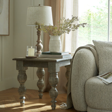 Hill Interiors Velantha table lamp with sculptural turned brown resin base and edged linen shade, styled on a rustic side table by a sunlit window.