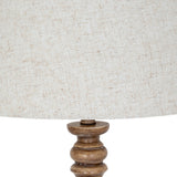 Close-up of the Hill Interiors Velantha floor lamp showing its turned brown resin base and edged natural linen drum shade against a white background.