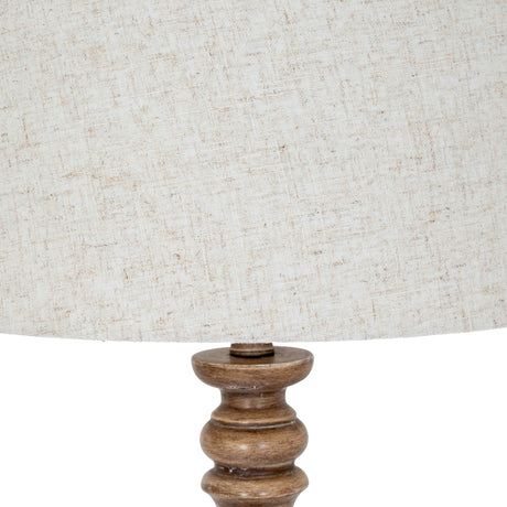 Close-up of the Hill Interiors Velantha floor lamp showing its turned brown resin base and edged natural linen drum shade against a white background.