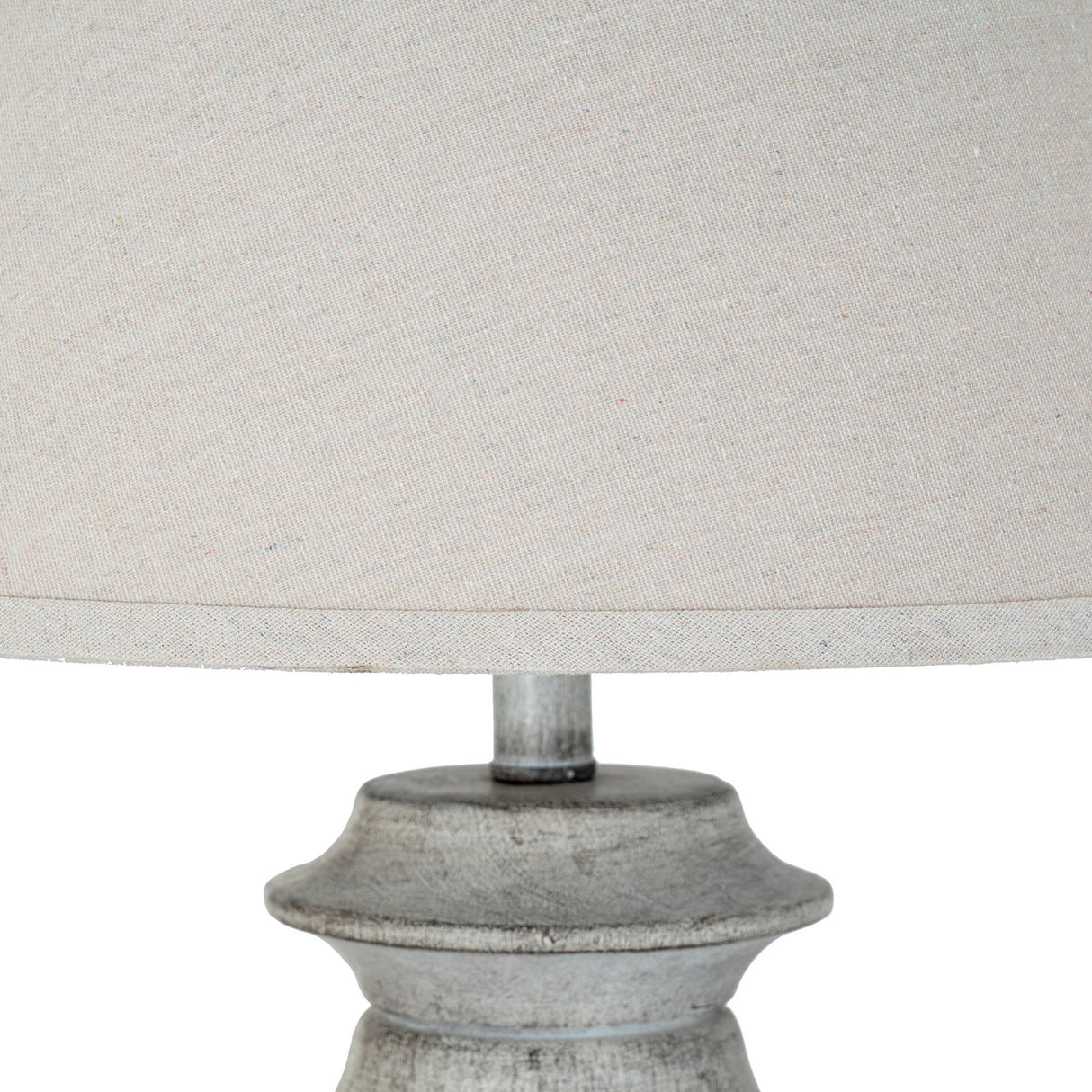 Close-up of Hill Interiors Table Lamp with natural linen drum shade and sculpted white resin base with a weathered grey finish.