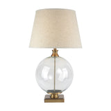 Hill Interiors Glass Orb Table Lamp with clear round glass base, brass-finished detail, square base and natural edged linen shade on a white background.