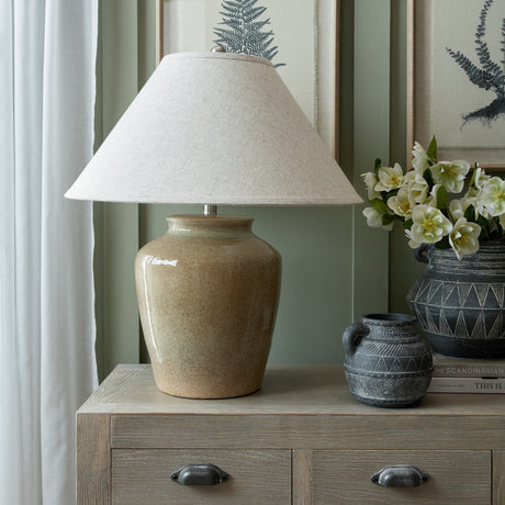 Hill Interiors ceramic table lamp in glazed green with a tapered edged linen shade, styled on a wooden sideboard beside dark patterned vases.