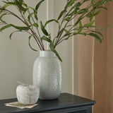 Hill Interiors Large Dimpled Ceramic Vase in white holding tall leafy stems, styled with a small stone pot on a dark console table.