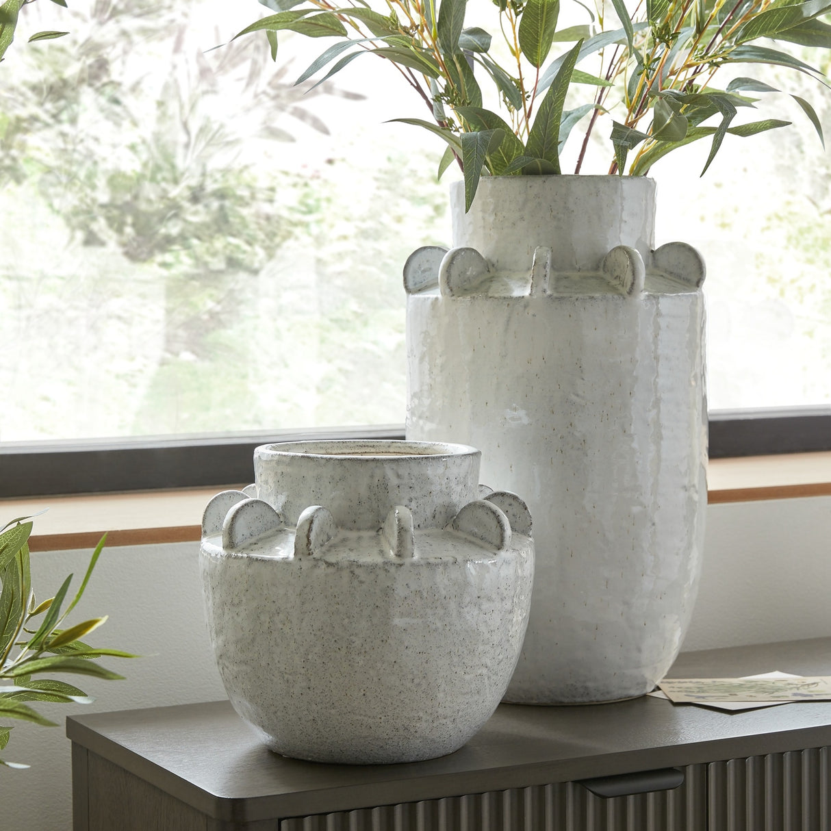 Hill Interiors Large Hydria ceramic vase in white with scalloped rim detail, shown with tall eucalyptus stems beside a smaller matching vessel on a windowsill.