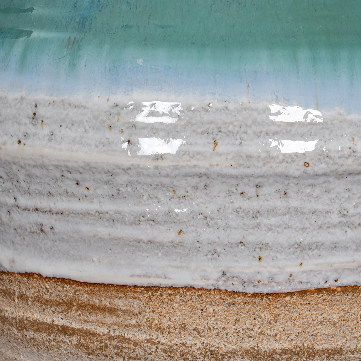 Close-up of the Hill Interiors ceramic amphora vase showing textured white glaze transitioning into a turquoise drip finish above a raw sandy base.