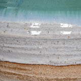 Close-up of the Hill Interiors ceramic amphora vase showing textured white glaze transitioning into a turquoise drip finish above a raw sandy base.
