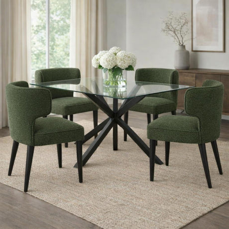 Hill Interiors Quennomer dining chairs in moss green bouclé upholstery with black tapered legs, arranged around a glass table in a neutral dining room.