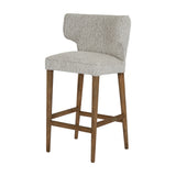 Hill Interiors Quennomer bar stool with grey textured upholstered wingback seat and solid wood legs with footrest, on a plain white background.