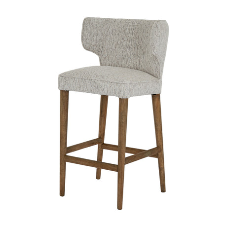 Hill Interiors Quennomer bar stool with grey textured upholstered wingback seat and solid wood legs with footrest, on a plain white background.