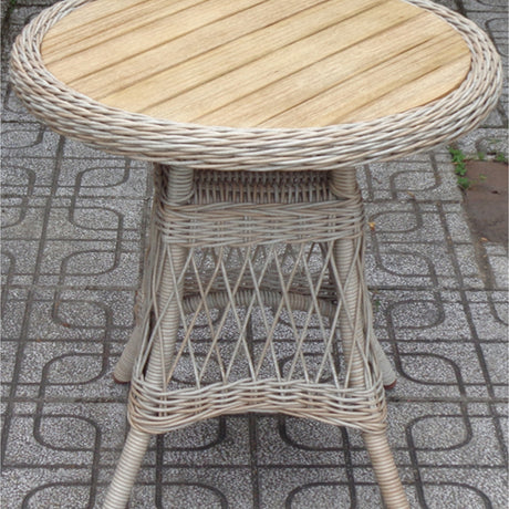 Round bistro table with woven beige rattan-style frame and slatted wooden top, shown on patterned paving in an outdoor setting.