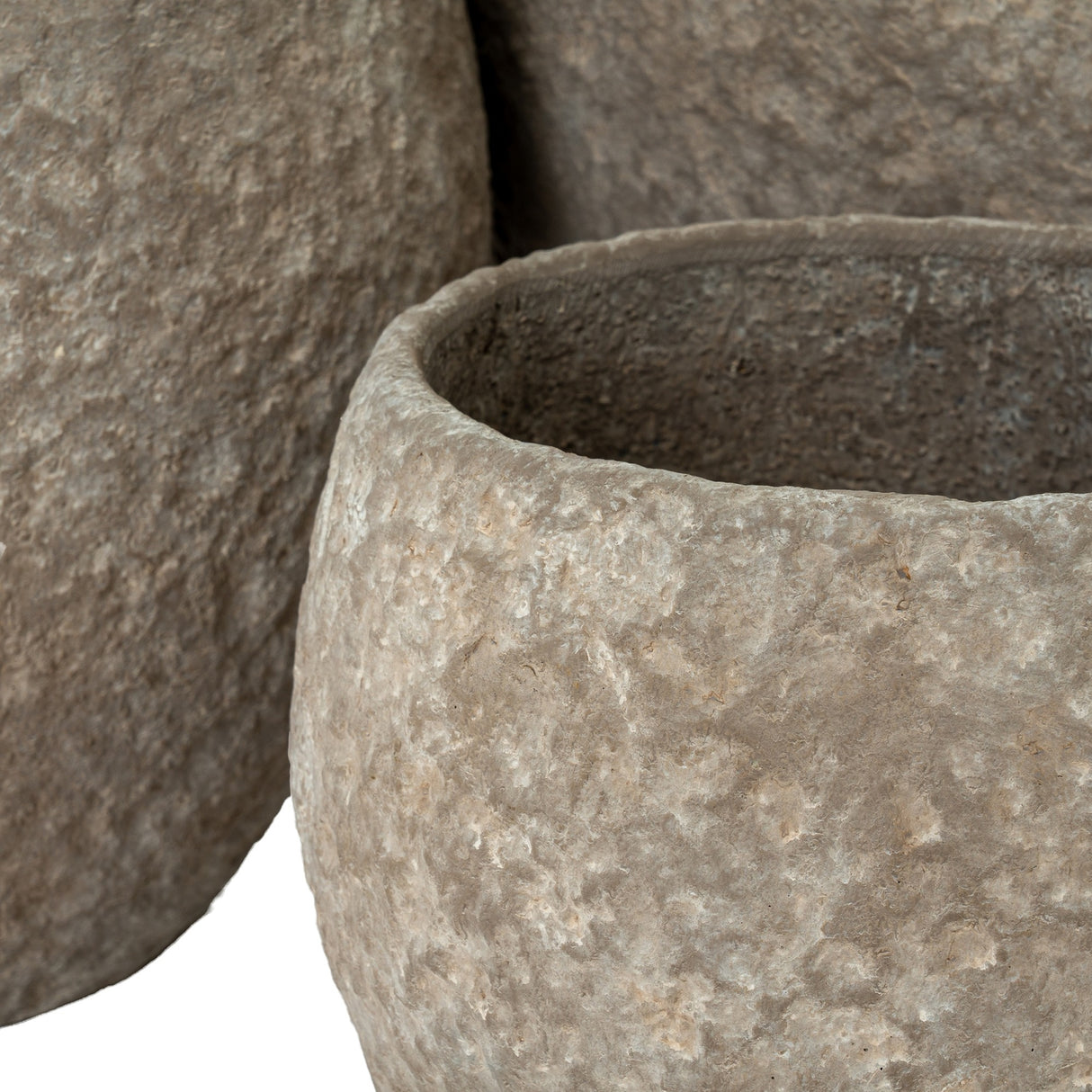 Close-up of Hill Interiors Pot Belly concrete planters in brown, showing the mottled textured surface and rounded forms with wide open tops.