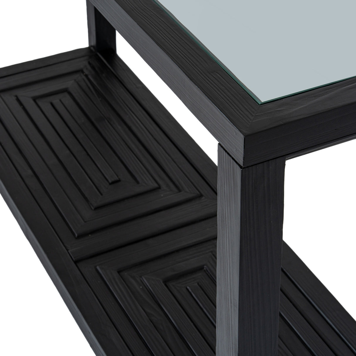 Close-up of the Hill Interiors Harweld black console table showing its toughened glass top, black frame, and geometric panel detail on the lower shelf.