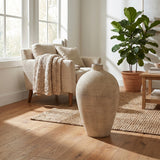 Hill Interiors Large Ceramic Vase in cream with a rounded body and tapered neck, placed on a jute rug beside a linen armchair in a sunlit living room.