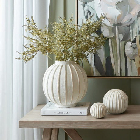 Hill Interiors ceramic globe vase in white with vertical ribbed detail, holding dried golden foliage on a console table beside two matching decorative spheres.