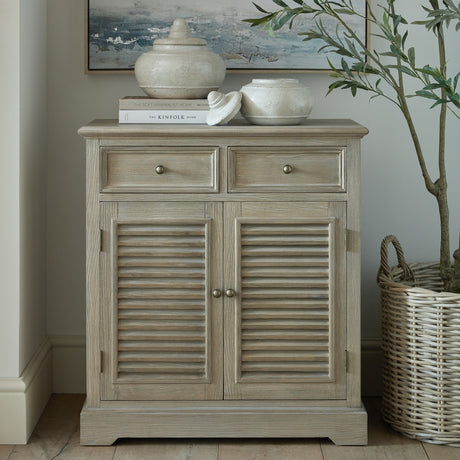 Hill Interiors Wooden Louvred Two-Door Chest in brown with two top drawers and shutter-style lower doors, styled with vases and books in a hallway.