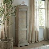 Hill Interiors 1 Door Tall Cabinet in brown wood with louvred door, styled by a window with linen curtains, olive tree and books on top.