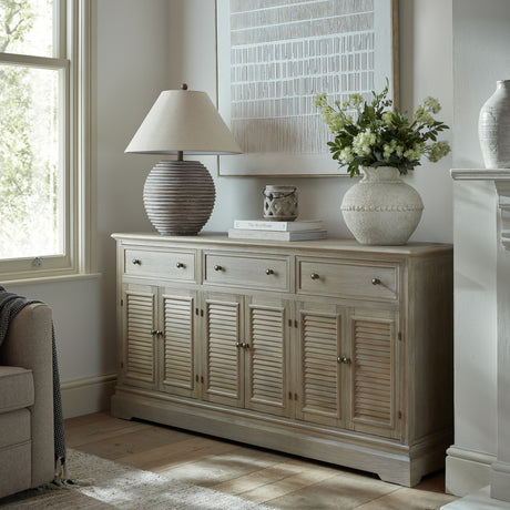 Hill Interiors 6 Door 3 Drawer Large Wooden Dresser Base in brown with louvred doors, styled in a living room with a lamp, vase and artwork.