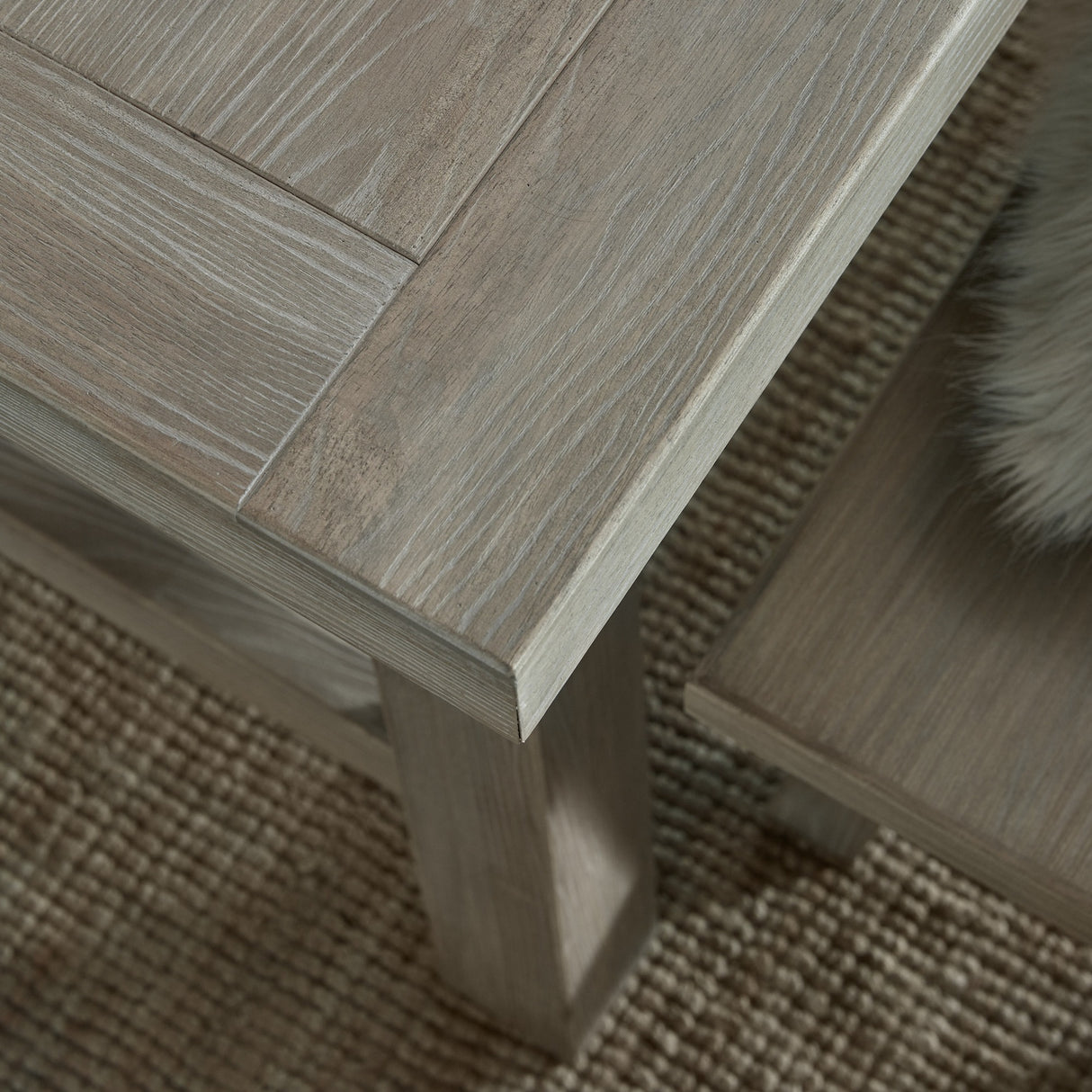 Close-up of the Hill Interiors Large Wooden Dining Bench in brown, showing the solid wood grain, panelled top edge and square leg on a woven rug.
