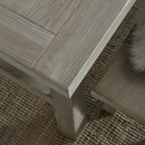 Close-up of the Hill Interiors Large Wooden Dining Bench in brown, showing the solid wood grain, panelled top edge and square leg on a woven rug.