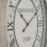 Close-up of Hill Interiors Large Round Wall Clock with grey wooden frame, glass face, Roman numerals, black hands, and Grand Hotel Paris lettering.