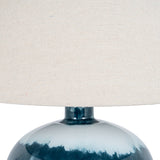 Close-up of Hill Interiors Squat Glass Table Lamp in blue, showing the rounded glossy glass base and natural linen drum shade.