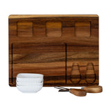 Hill Interiors acacia wood cheese board with recessed sections, three stacked white ceramic bowls and two wooden-handled cheese knives on a white background.