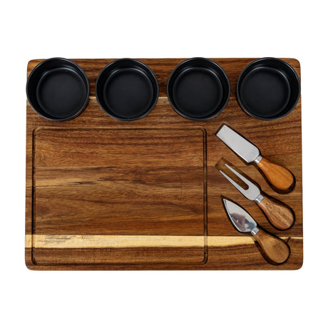 Hill Interiors acacia cheese board set with four black ceramic bowls and three wooden-handled cheese knives arranged on the brown wooden board.