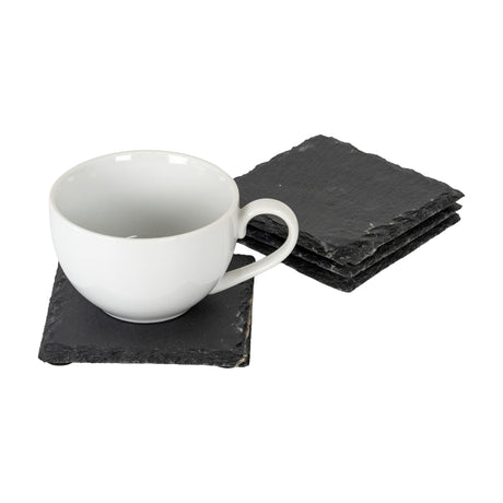 Hill Interiors Set of Four Square Slate Coasters in black, stacked beside a white ceramic mug resting on a single coaster against a plain white background.