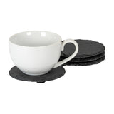 Hill Interiors Set of Four Round Slate Coasters in black, shown with a white ceramic teacup resting on one coaster and three stacked alongside.