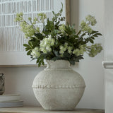 Hill Interiors medium stone-effect ceramic vase in white with textured beaded band, holding green foliage and blooms on a sideboard beside framed art.