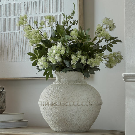 Hill Interiors medium stone-effect ceramic vase in white with textured beaded band, holding green foliage and blooms on a sideboard beside framed art.