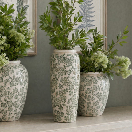 Hill Interiors Large Tall Ceramic Clover Olpe Vases in white with green floral patterning, displayed with leafy foliage on a mantel against botanical prints.
