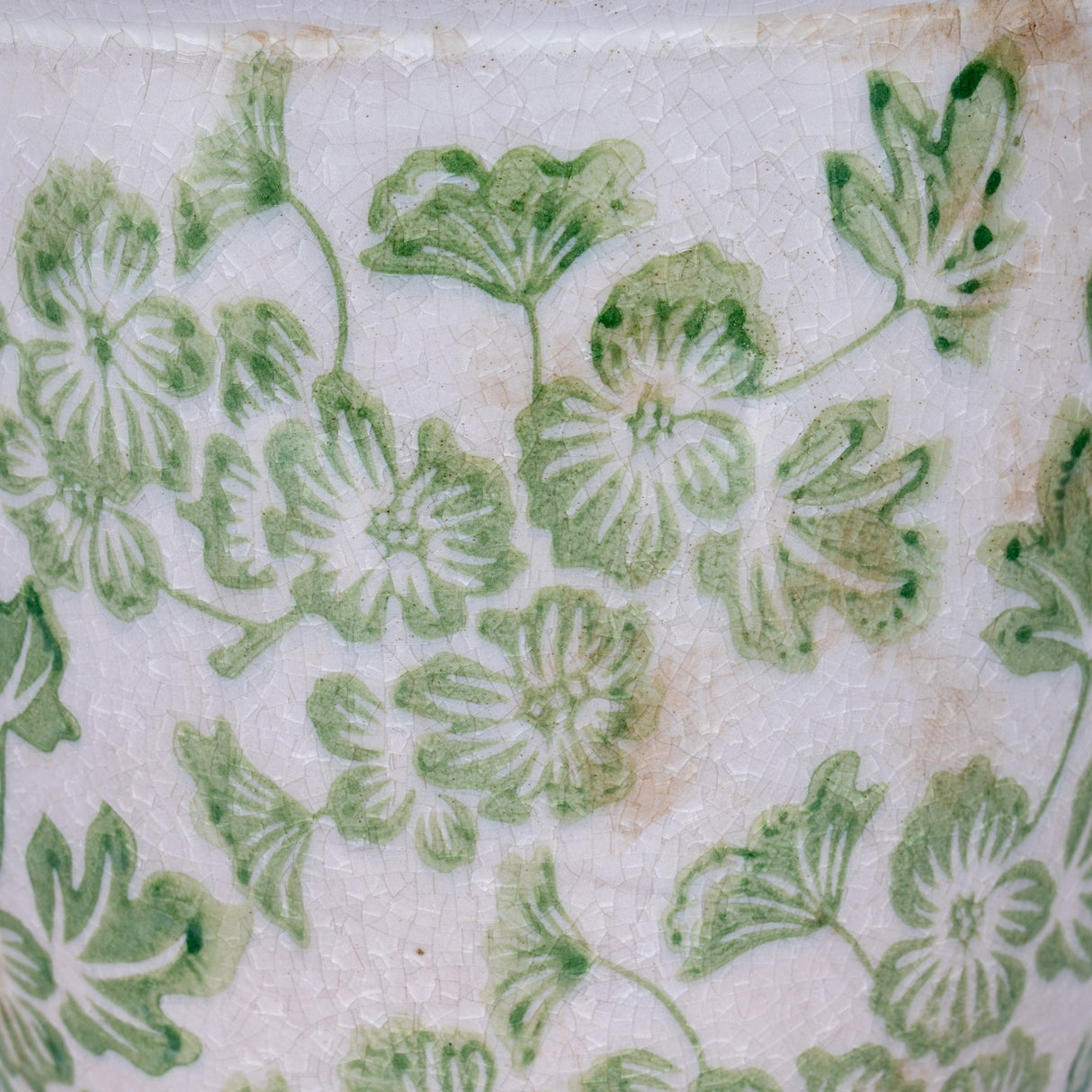 Close-up of the Hill Interiors Small Ceramic Clover Planter showing green floral motifs on a crackle-glazed white surface.