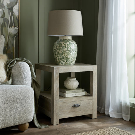 Hill Interiors Ceramic Pot Table Lamp with green floral glaze and neutral drum shade, styled on a light oak side table in a green living room.