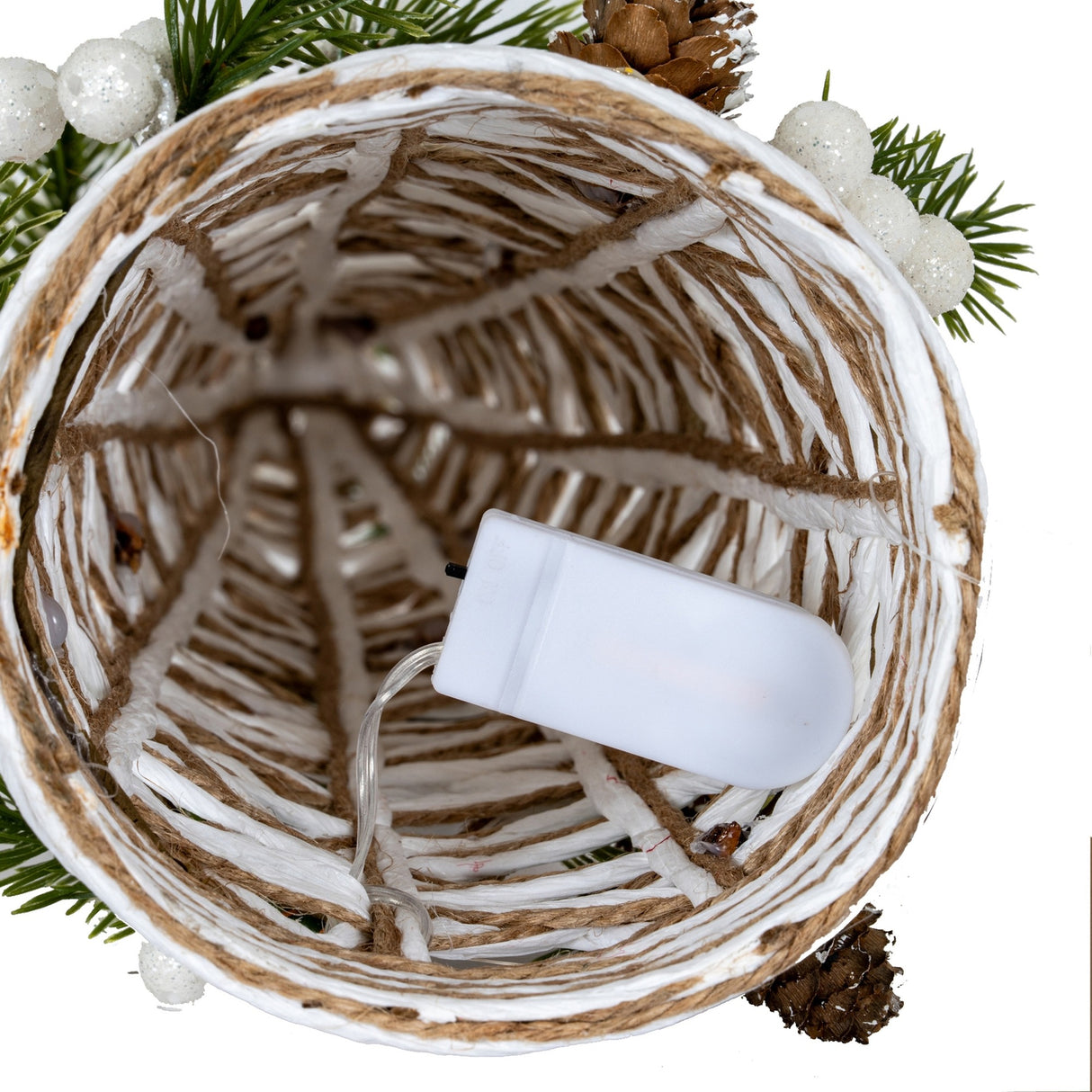 Top-down view into the open base of Hill Interiors' white rattan LED cone tree, showing woven strands, jute cord and a battery pack.