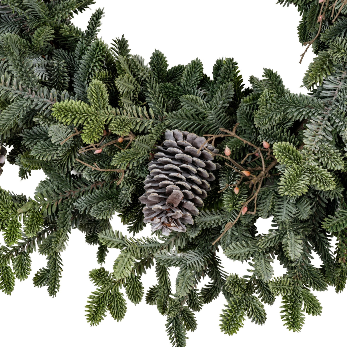 Close-up of Hill Interiors Woodland Pine Wreath in green with layered faux pine sprigs, a large grey cone and small berries on a white background.