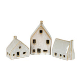 Hill Interiors Ceramic Cottage With LED Light in white, shown as three glazed miniature houses with pitched roofs, chimneys and cut-out windows on white.