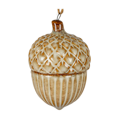 Hill Interiors ceramic acorn ornament with a cross-hatched cap and ribbed body in a warm cream and tan glaze, hung from twine against a white background.