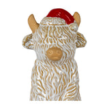 Hill Interiors ceramic Highland cow ornament in white glazed finish with textured shaggy coat, horns and a red Santa hat, on a plain background.