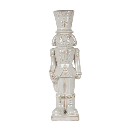 Hill Interiors Ceramic Nutcracker With Stocking in white, a tall glazed figure with crown hat, moustache and soldier uniform, on a plain background.