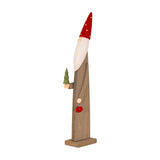 Hill Interiors wooden festive elf in brown with a red polka dot hat, white beard, holding a green tree and a red jingle bell, on a plain background.