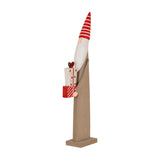 Hill Interiors Wooden Festive Elf with Presents in brown, with a striped red and white pointed hat, holding wrapped gifts, on a plain background.