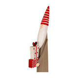 Hill Interiors wooden festive elf in brown with a red and white striped pointed hat, long white beard, holding stacked star-patterned gifts, on white.