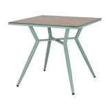 Hill Interiors French Grey square side table with tempered glass top over a beige surface and slender pale green metal legs on a white background.