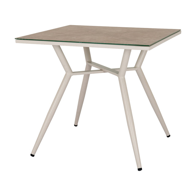 Hill Interiors square side table with a beige glass top and slim tapered cream metal legs joined by a cross stretcher, on a plain white background.