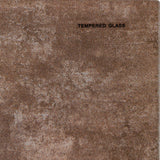 Close-up of the Hill Interiors Round Glass Side Table in beige, showing the mottled putty-toned tempered glass surface with a small printed label.
