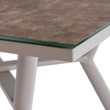 Close-up of Hill Interiors Round Glass Side Table in beige, showing the tempered glass top edge over a stone-effect surface and pale angled legs.