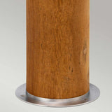 A close-up of the Hornsea 1 Light Bollard in brown, featuring a teak wood cylindrical pole with a smooth, natural finish, mounted on a sleek stainless steel base. The background is simple and neutral gray.