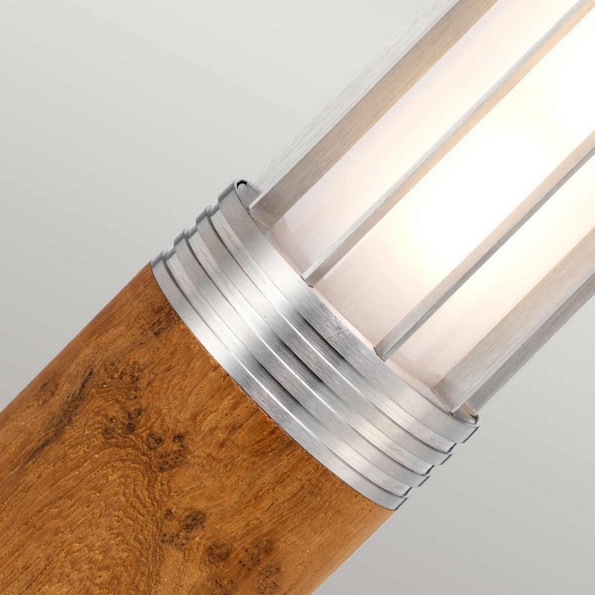 Close-up of the Hornsea 1 Light Bollard in brown, showcasing a teak wood base complemented by a polished stainless steel accent and a frosted cylindrical light shade. This design merges natural and modern elements, providing a soft, warm glow ideal for outdoor lighting.