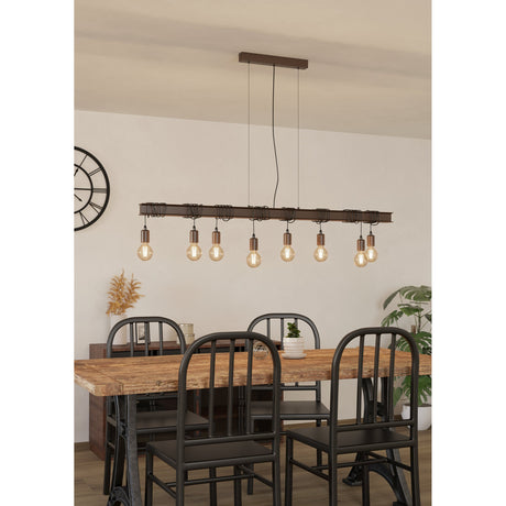 Hosmane 8-light linear pendant light with an antique brown steel beam, looped black cable detailing, and exposed E27 bulbs, shown above a dining table with black chairs.
